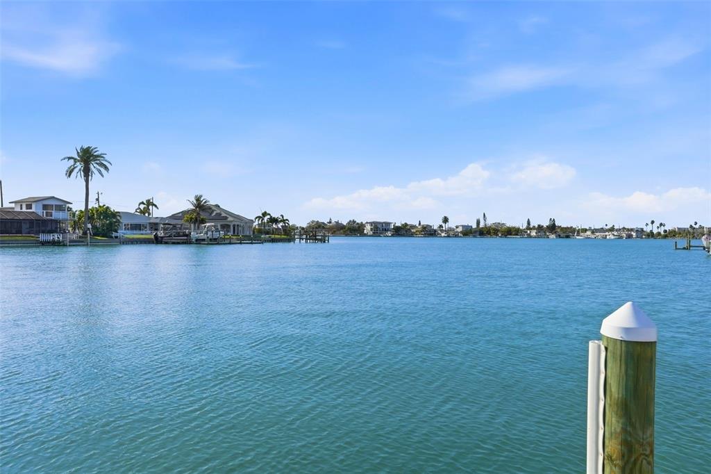Two white rocking chairs and a small table sit on a patio overlooking water — 6420 3RD PALM POINT, ST PETE BEACH, FL