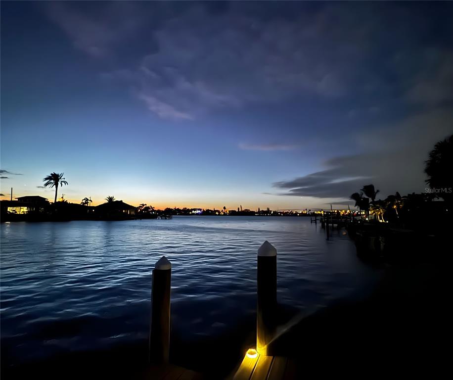 An aerial view of a waterfront neighborhood with houses, boat docks, and the ocean beyond — 6420 3RD PALM POINT, ST PETE BEACH, FL