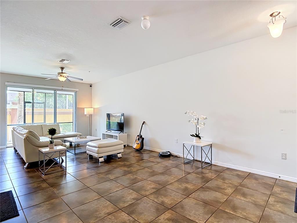 A living room with tile floors, a white sectional sofa, and stairs leading upstairs — 8615 ANDALUCIA FIELD DRIVE, TAMPA, FL