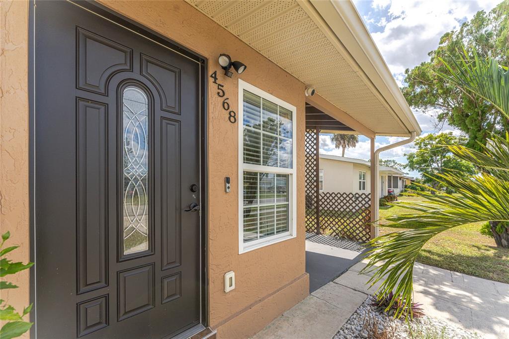 A dark brown front door with a glass insert sits beside a window and address numbers — 4568 GROBE STREET, NORTH PORT, FL