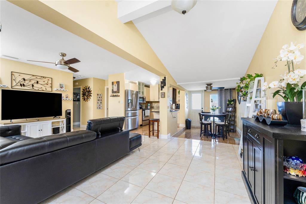 An open-concept living room and kitchen featuring light tile floors and vaulted ceilings — 4568 GROBE STREET, NORTH PORT, FL