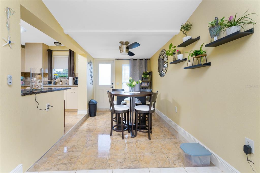 A dining area with tile floors, a round table, and wall-mounted shelves featuring potted plants — 4568 GROBE STREET, NORTH PORT, FL