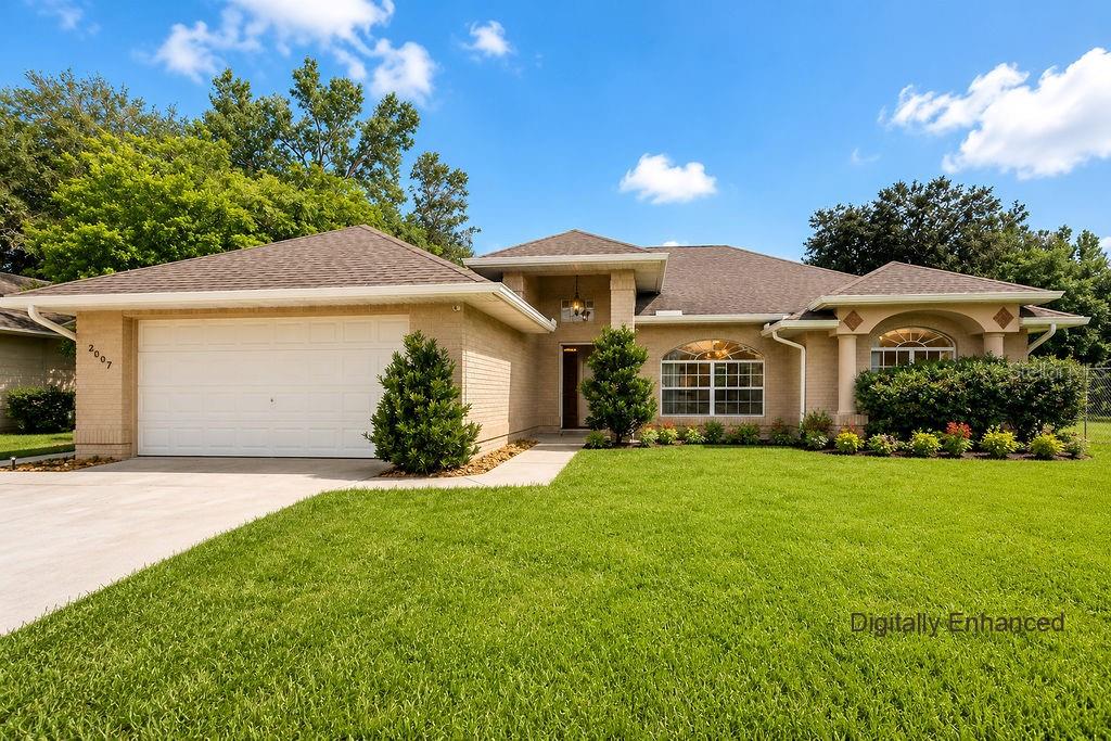 A single-story brick house features a two-car garage, a covered entryway, and a manicured lawn — 2007 N PARKTON DRIVE, DELTONA, FL