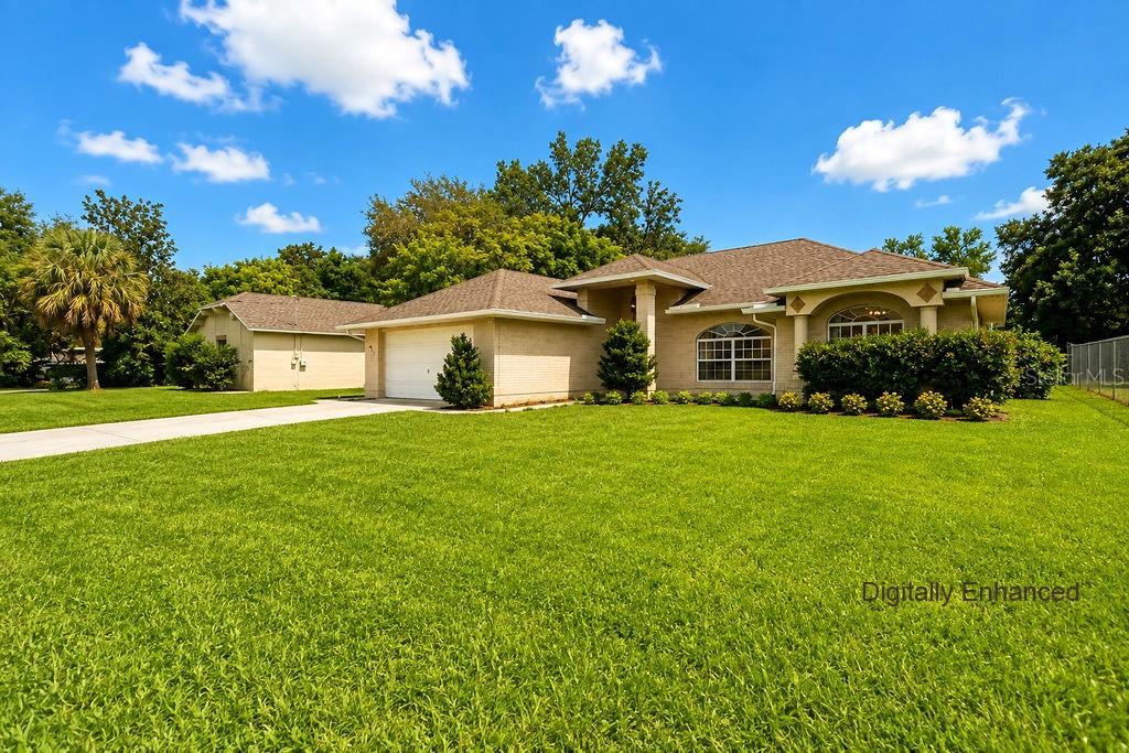 A single-story brick house with a two-car garage and a large front lawn — 2007 N PARKTON DRIVE, DELTONA, FL