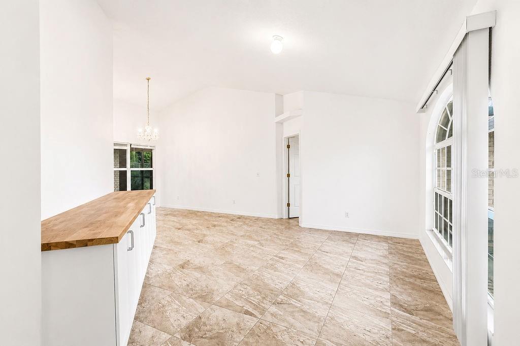 An empty room with light tile flooring, white walls, a wooden counter, and arched windows — 2007 N PARKTON DRIVE, DELTONA, FL