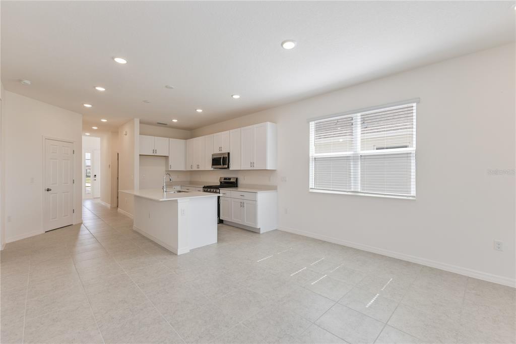 A bright kitchen features white cabinets, a central island, and light-colored tile flooring — 9120 WILDLIGHT TRAIL, WILDWOOD, FL