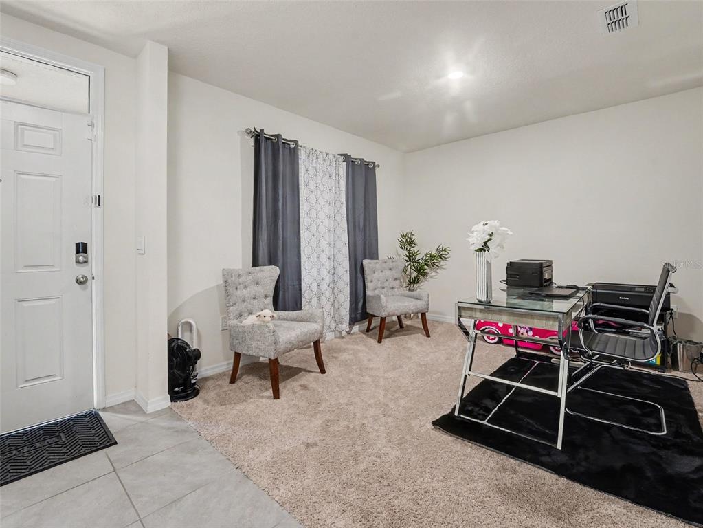 A home office features a glass desk, two gray tufted chairs, and carpeted flooring — 210 MEADOWBROOK BOULEVARD, WINTER HAVEN, FL