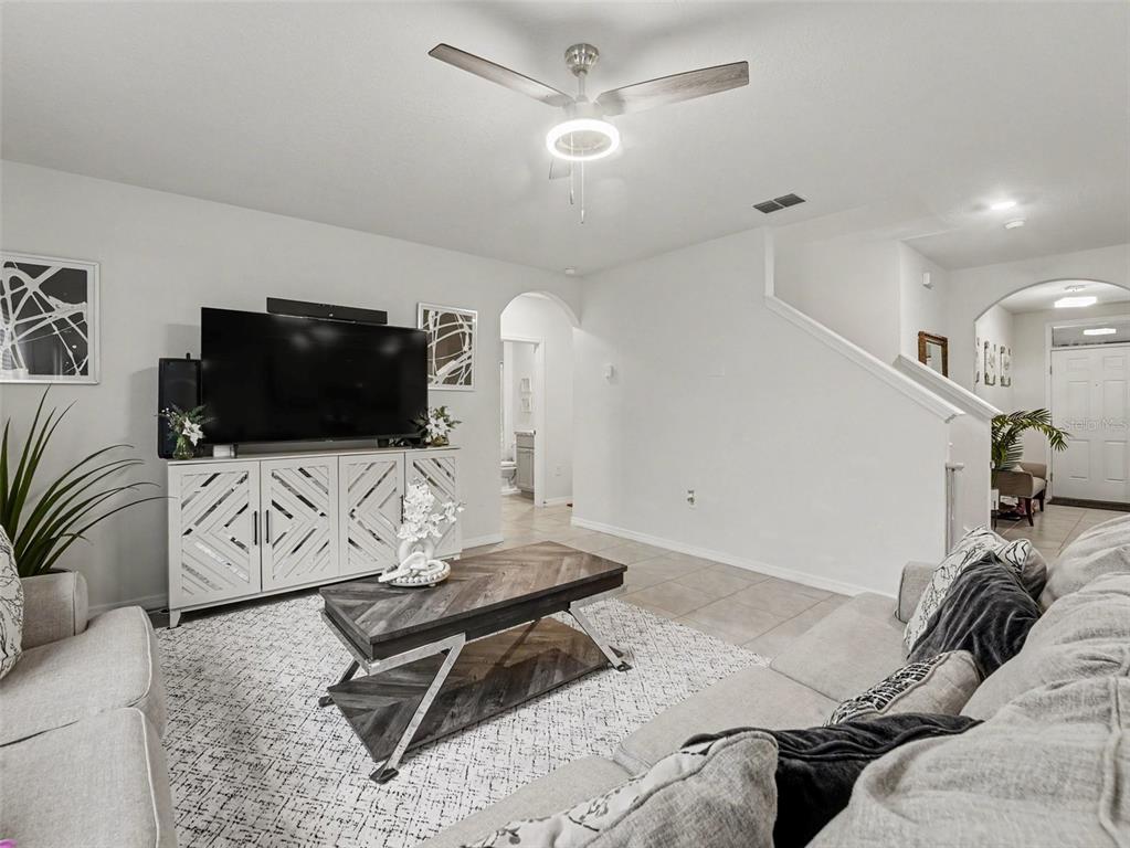 A living room features a television on a white cabinet, a coffee table, and stairs — 210 MEADOWBROOK BOULEVARD, WINTER HAVEN, FL