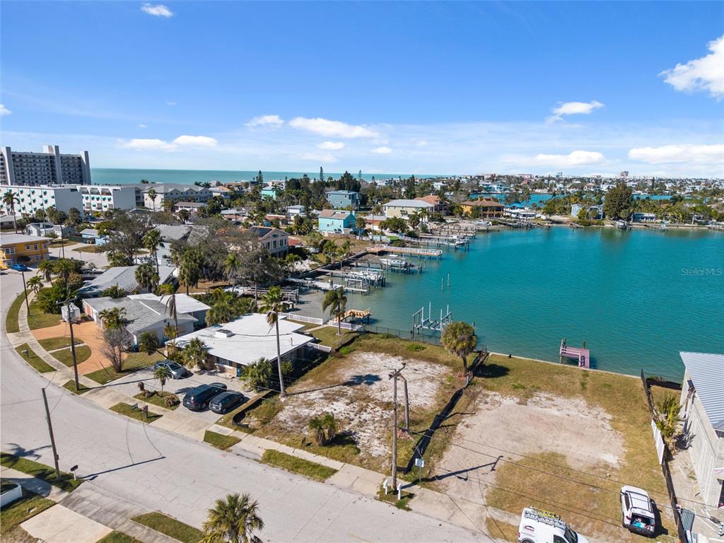 An aerial view shows a vacant waterfront lot next to a house and boat docks — 15307 HARBOR DRIVE, MADEIRA BEACH, FL