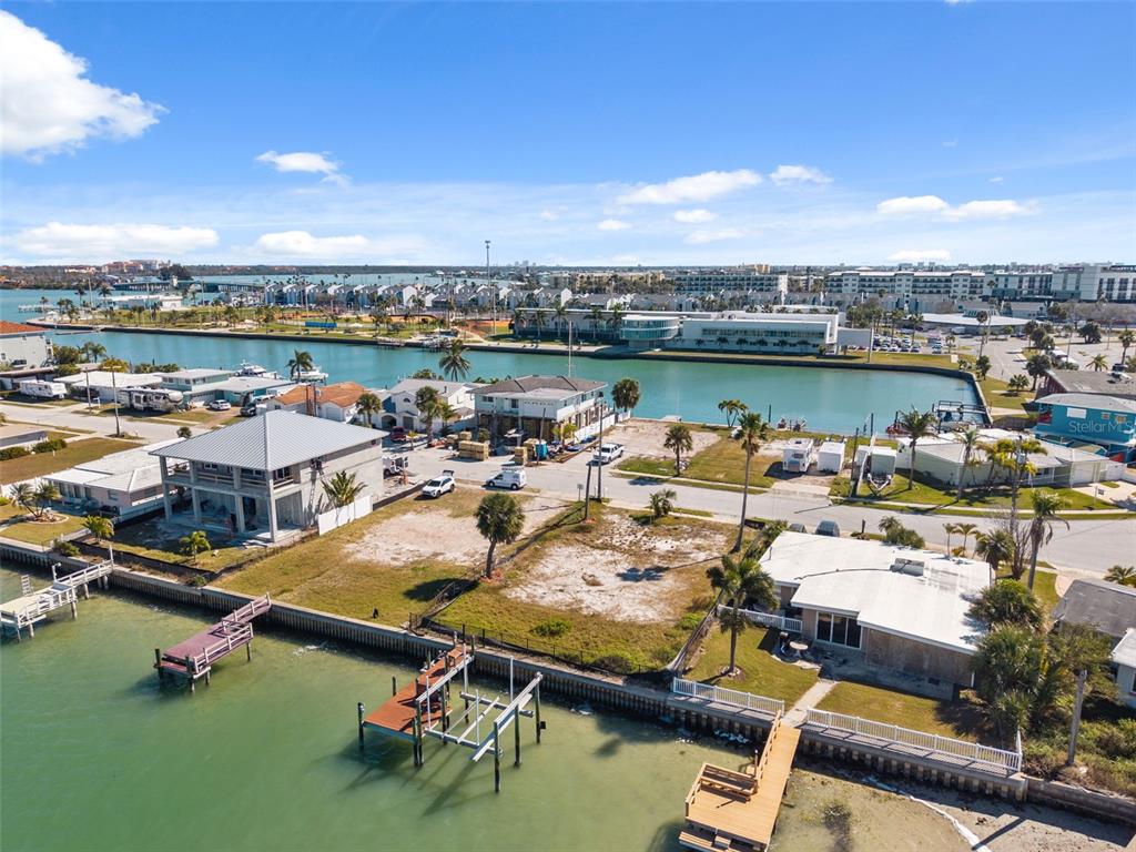 An aerial view shows waterfront homes, vacant lots, and boat docks along a canal — 15307 HARBOR DRIVE, MADEIRA BEACH, FL