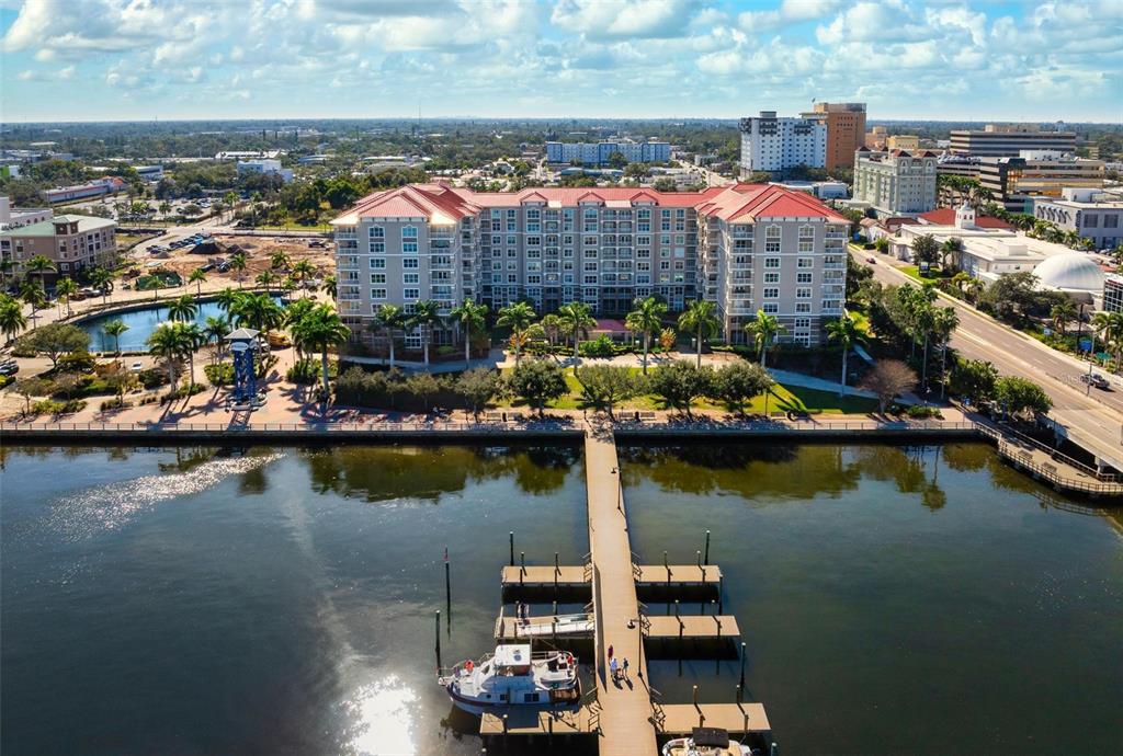 An aerial view shows a large multi-story residential building situated along a waterfront with docks — 808 3RD AVENUE W UNIT 402, BRADENTON, FL