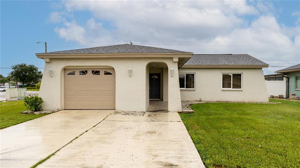 A single-story house with a tan stucco exterior, a one-car garage, and a concrete driveway — 4802 RIDGE POINT DRIVE, TAMPA, FL