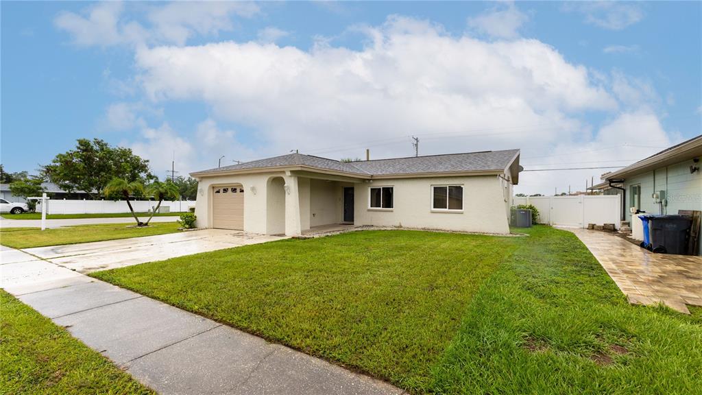 A single-story house with a beige stucco exterior, a one-car garage, and a front lawn — 4802 RIDGE POINT DRIVE, TAMPA, FL