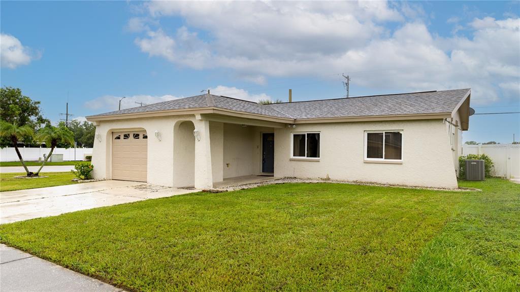A single-story house with a beige stucco exterior, a one-car garage, and a front lawn — 4802 RIDGE POINT DRIVE, TAMPA, FL