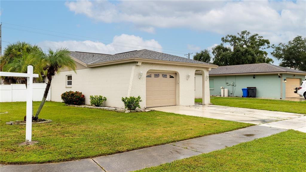 A single-story house with a beige block exterior, a garage, and a palm tree in front — 4802 RIDGE POINT DRIVE, TAMPA, FL