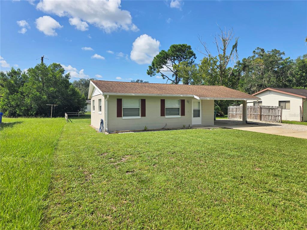 A single-story house with a tan exterior, brown roof, and attached carport sits on grass — 185 E LAKE MARY AVENUE, LAKE MARY, FL