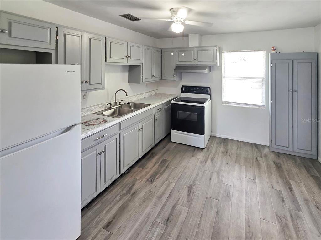 A kitchen features gray cabinets, white appliances, laminate countertops, and wood-look flooring — 185 E LAKE MARY AVENUE, LAKE MARY, FL