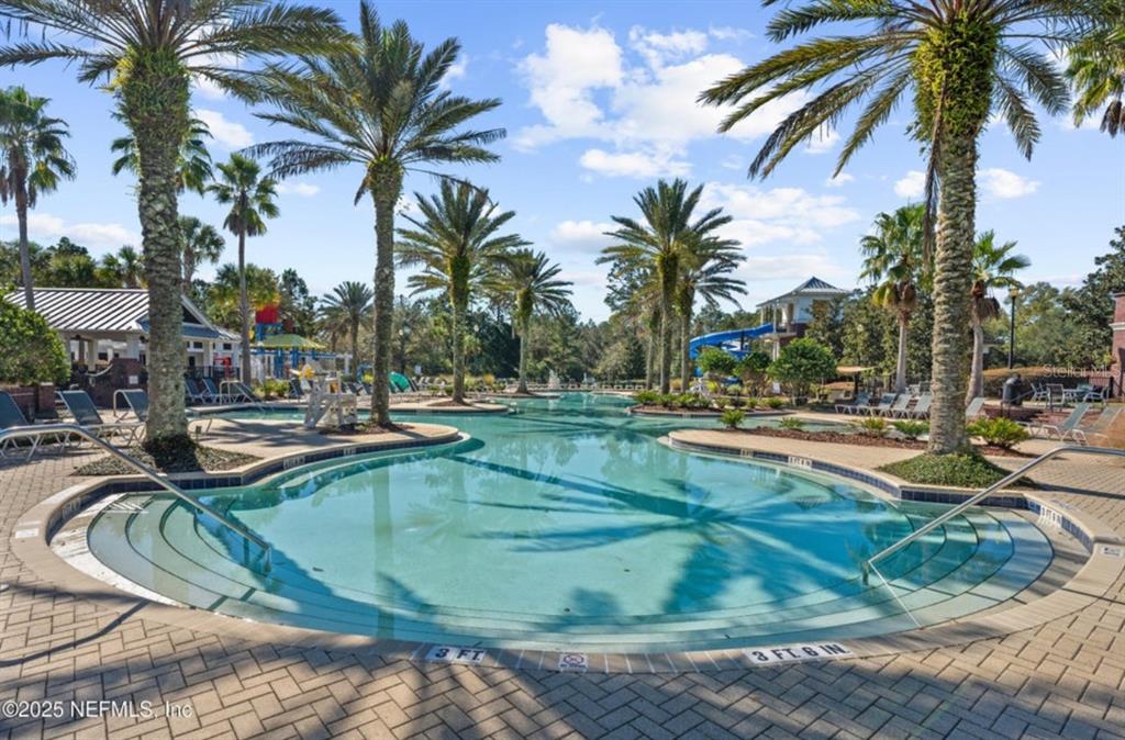 An aerial view shows a community pool complex with water slides, a clubhouse, and landscaping — 585 RUNNING WOODS STREET, ORANGE PARK, FL