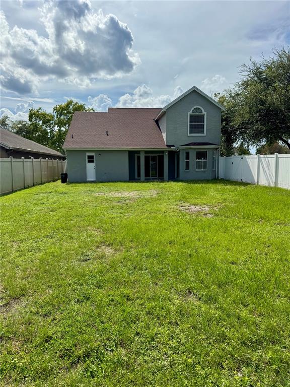 The exterior view shows the back of a two-story house with a large grassy yard — 12509 CRAYFORD AVENUE, ORLANDO, FL