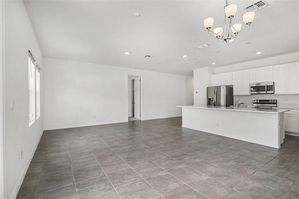 A single-story house with a beige garage, light-colored siding, and a concrete driveway — 1034 ALABASTER WAY, DELTONA, FL