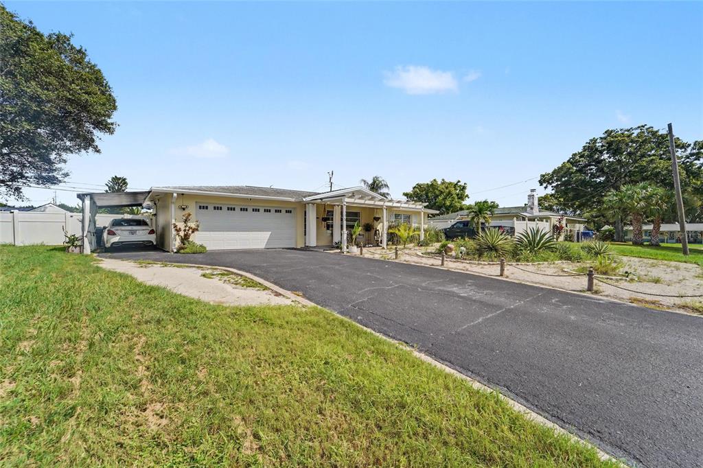 A covered patio features a patterned tiled floor, white columns, and a small garden bed — 1779 AVON LANE, LARGO, FL