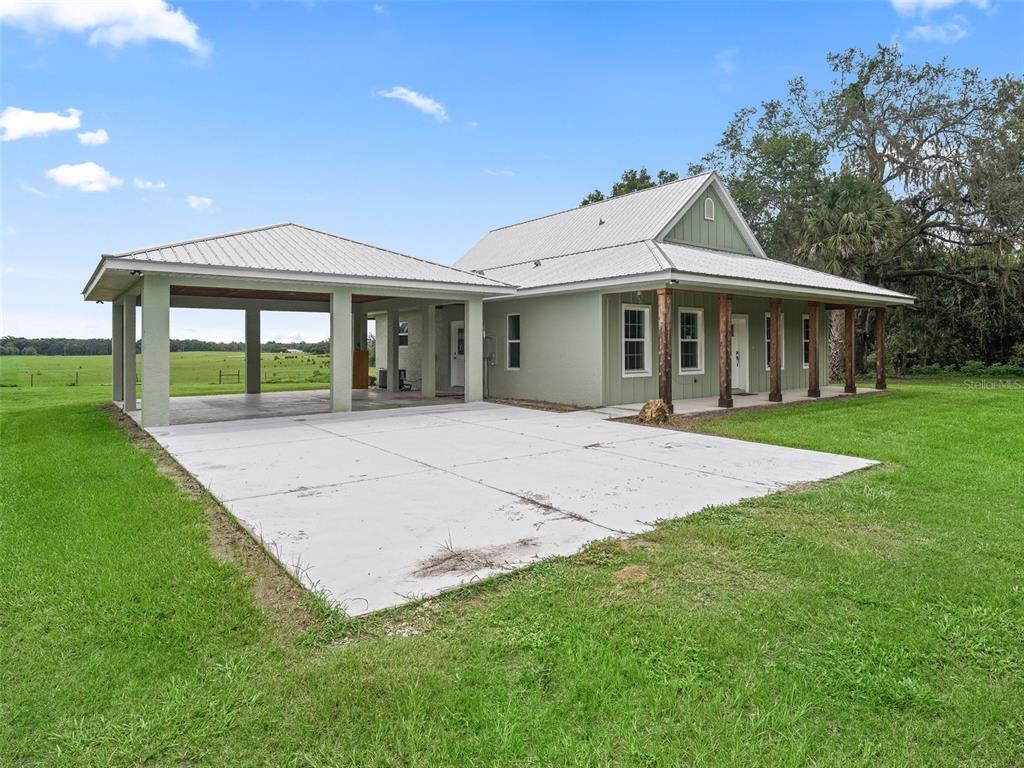 A light green house with a metal roof and an attached open-air carport — 8567 CR 635, BUSHNELL, FL