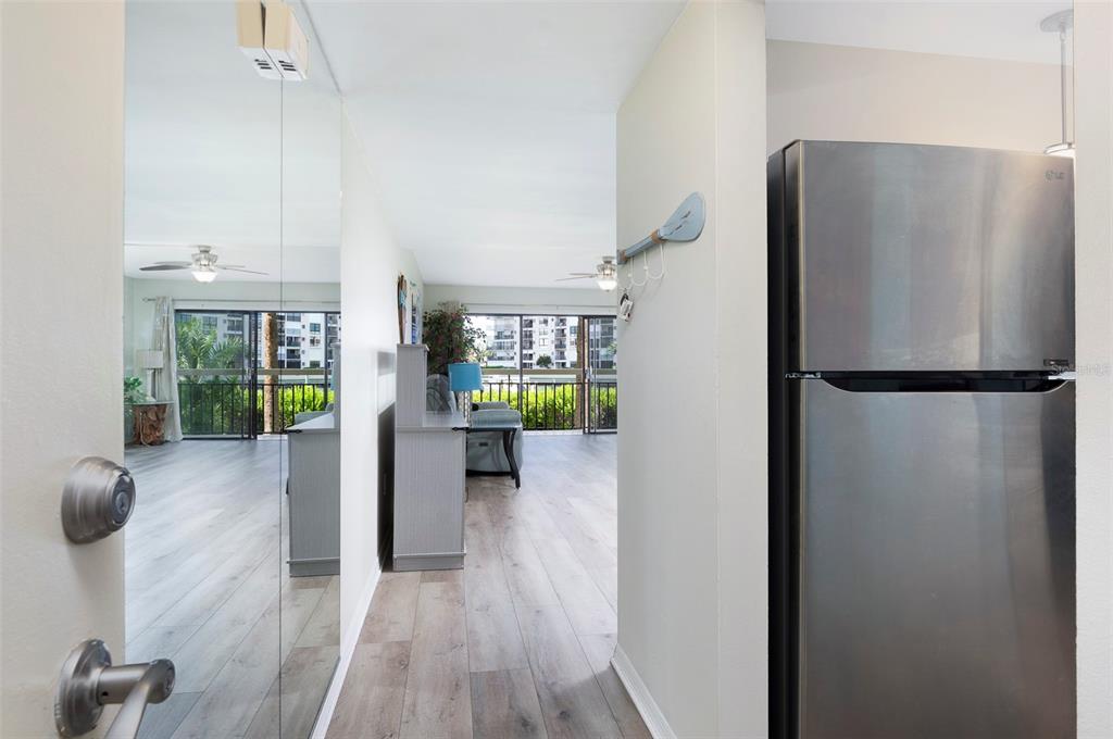 A hallway with a mirrored wall leads to a living area with a balcony view — 7903 SAILBOAT KEY BOULEVARD S UNIT 102, SOUTH PASADENA, FL