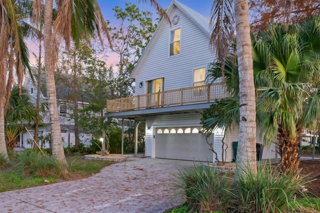 A two-story white house with a garage, a wooden balcony, and surrounding palm trees — 3403 10TH STREET W, PALMETTO, FL