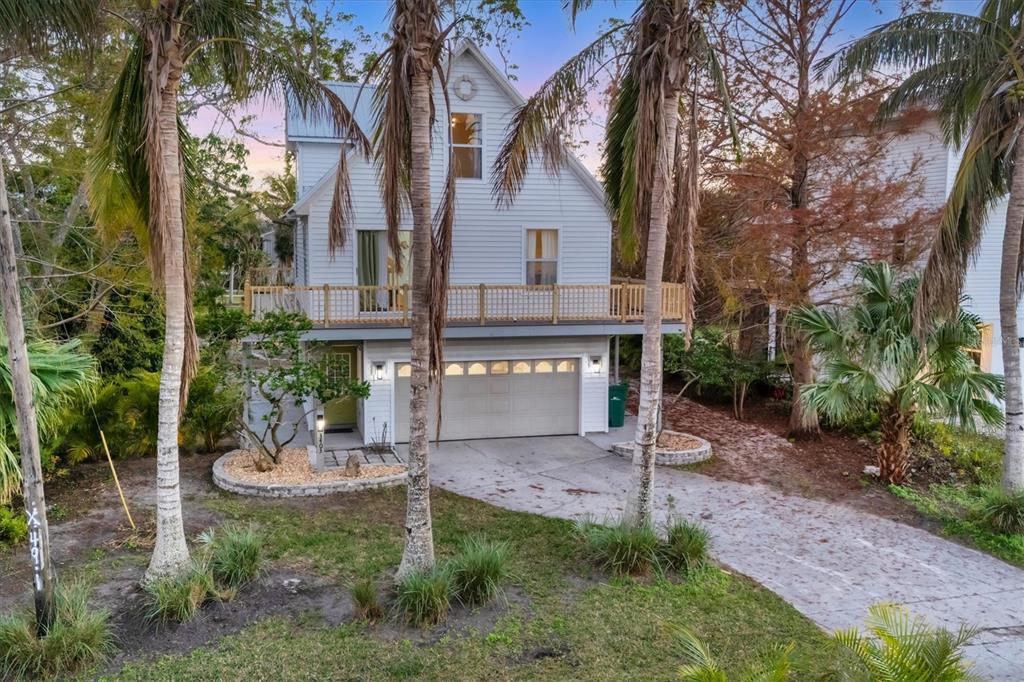 A two-story white house with a garage, a balcony, and palm trees in the yard — 3403 10TH STREET W, PALMETTO, FL