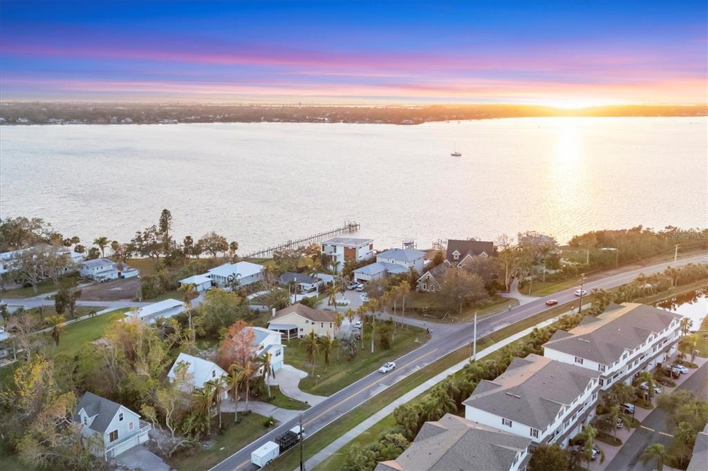 An aerial view shows a coastal neighborhood with houses, a road, and a large body of water — 3403 10TH STREET W, PALMETTO, FL
