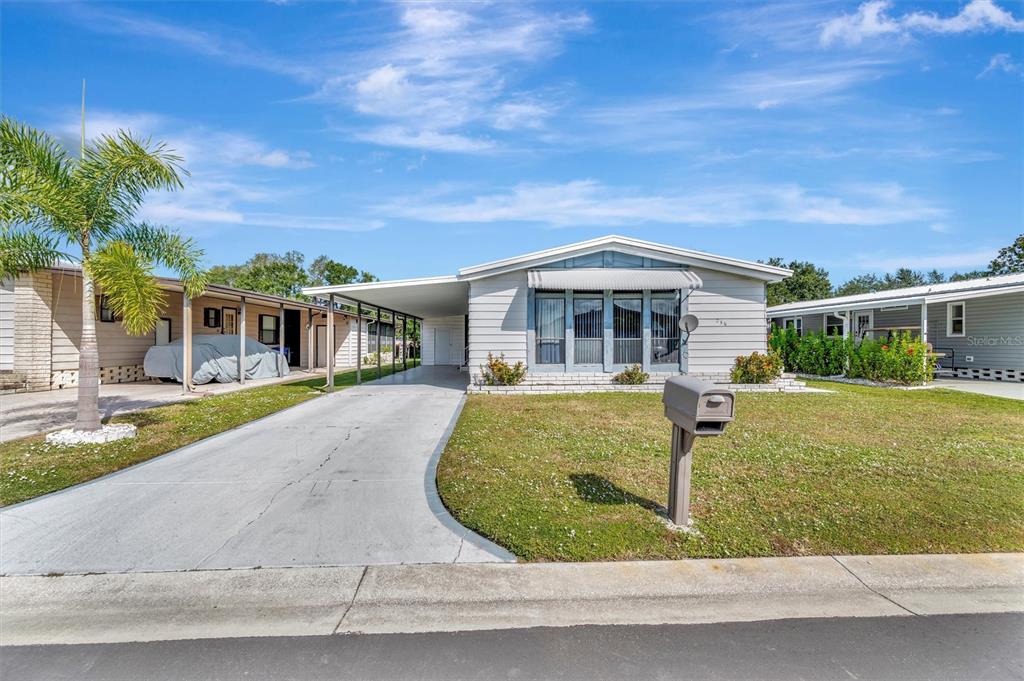 A light-colored single-story manufactured home features a concrete driveway, carport, and a front lawn — 236 N SAINT THOMAS CIRCLE, APOLLO BEACH, FL