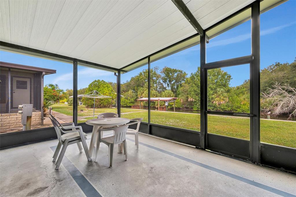 A screened-in patio with a concrete floor overlooks a grassy yard and a small canal — 236 N SAINT THOMAS CIRCLE, APOLLO BEACH, FL