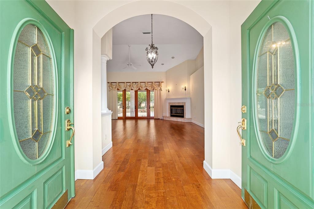 A view through double green front doors into a living room with hardwood floors — 7939 SE 12TH CIRCLE, OCALA, FL
