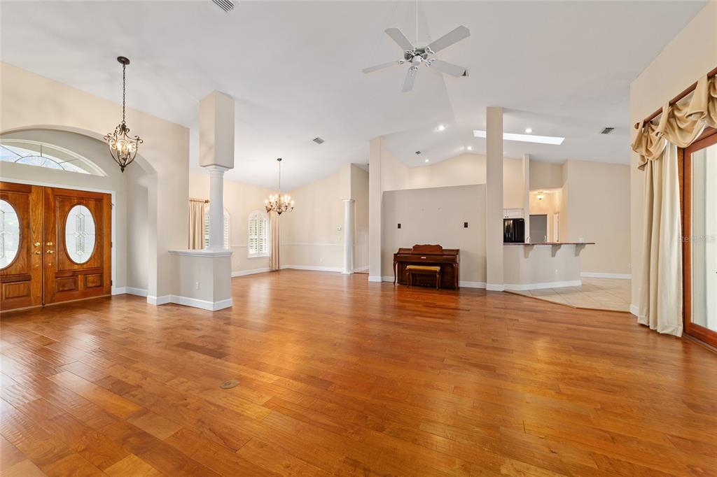 A spacious living area features hardwood floors, a piano, and an open kitchen with tile — 7939 SE 12TH CIRCLE, OCALA, FL