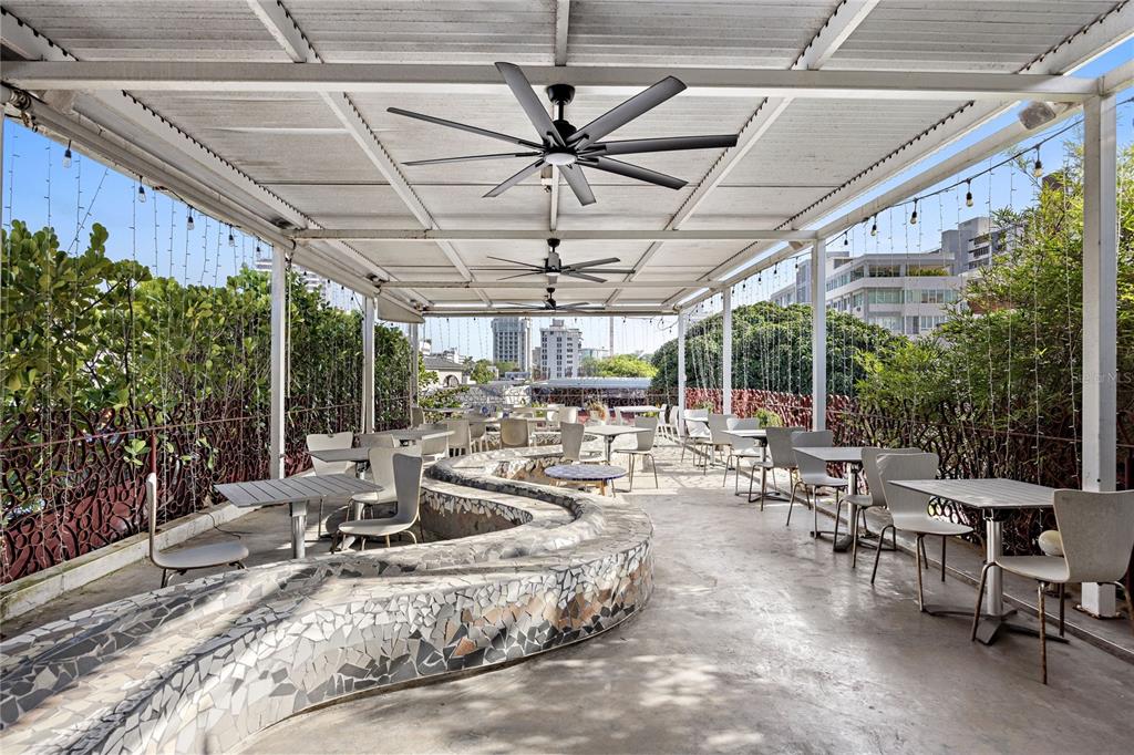 An outdoor covered patio features a winding mosaic bench, metal tables, and ceiling fans — 1105 MAGDALENA AVENUE UNIT Condal, SAN JUAN, PR