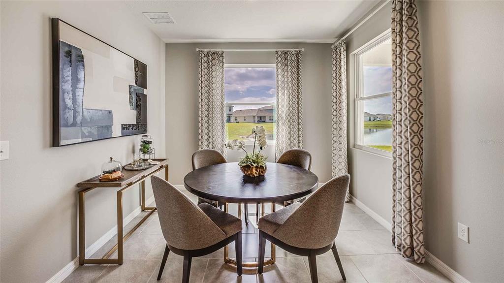 A dining room features a round table, four chairs, a console table, and two windows — 32645 DULUTH DRIVE, WESLEY CHAPEL, FL