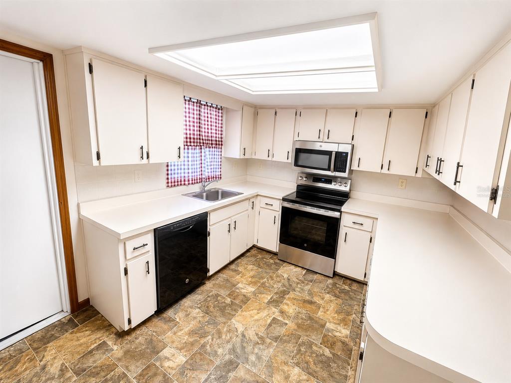 A living room with beige carpet, a sofa, an armchair, a coffee table, and a television — 3800 E SILVER SPRINGS BOULEVARD UNIT 8, OCALA, FL