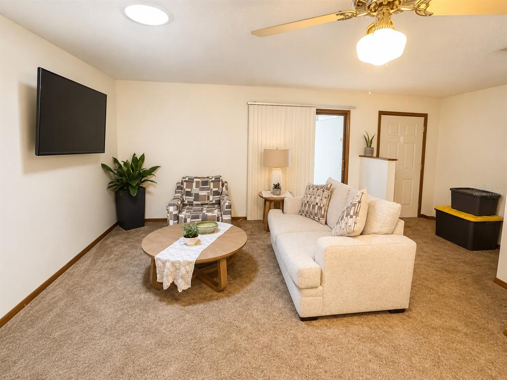 A bedroom features a white bed frame, green bedding, brown carpet, and a ceiling fan — 3800 E SILVER SPRINGS BOULEVARD UNIT 8, OCALA, FL