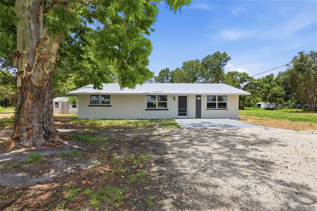 A single-story house with a light-colored exterior, metal roof, and a gravel driveway — 5587 SW HIGHWAY 17, ARCADIA, FL