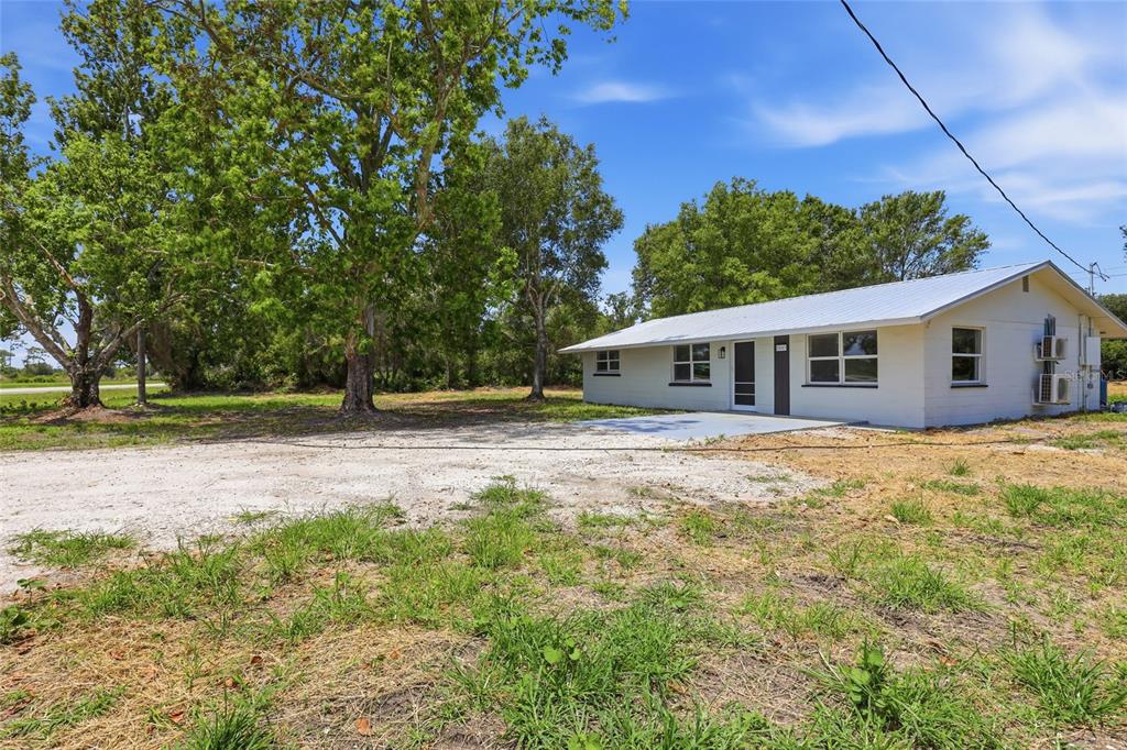 A white single-story house with a metal roof sits on a large, grassy dirt lot — 5587 SW HIGHWAY 17, ARCADIA, FL