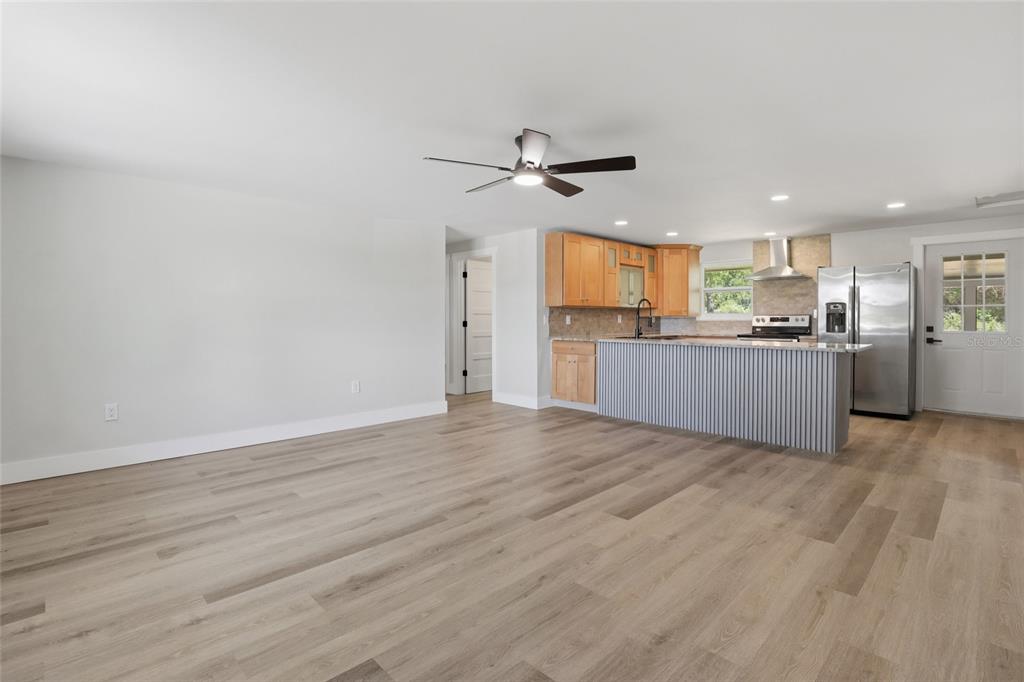 An open-concept living area features light wood-look flooring, a kitchen island, and stainless steel appliances — 5587 SW HIGHWAY 17, ARCADIA, FL