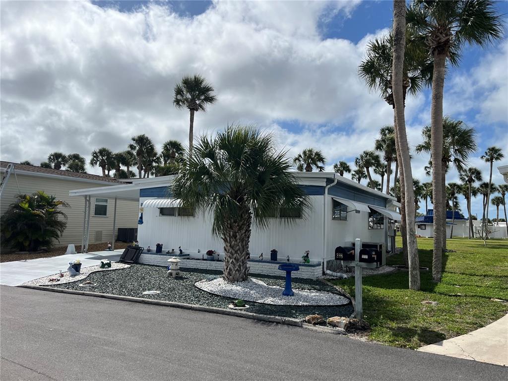 A white mobile home with a palm tree in the front yard under a cloudy sky — 206 ROMA ROAD, VENICE, FL