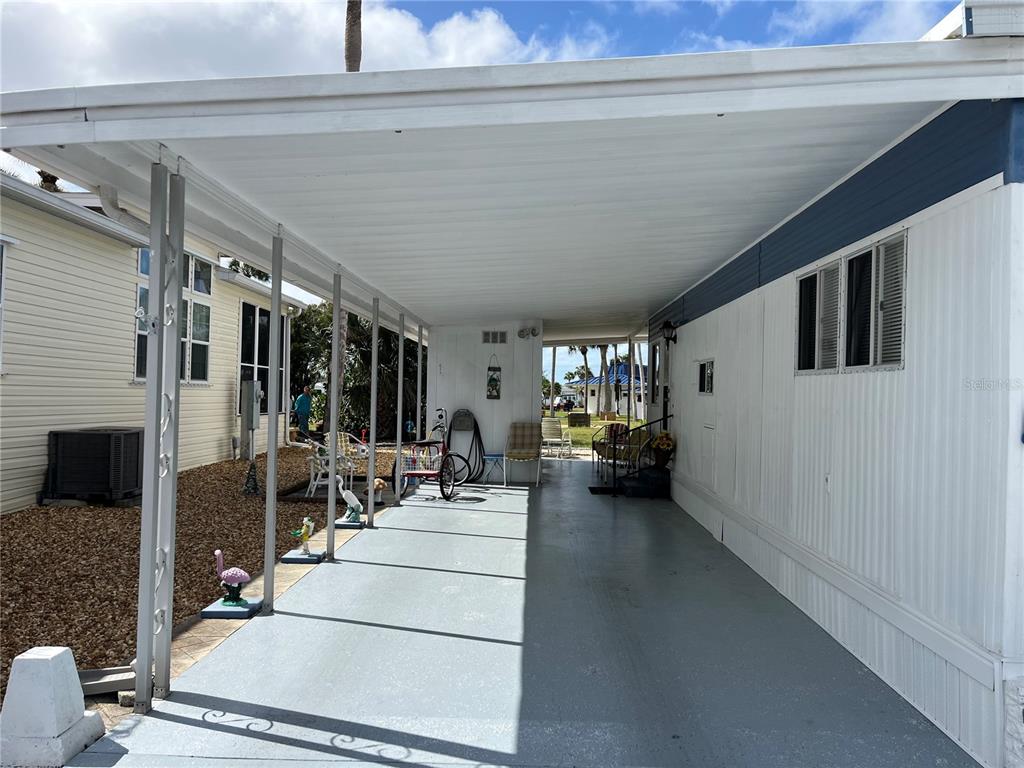 A covered carport area with a concrete floor sits between two mobile home exteriors — 206 ROMA ROAD, VENICE, FL