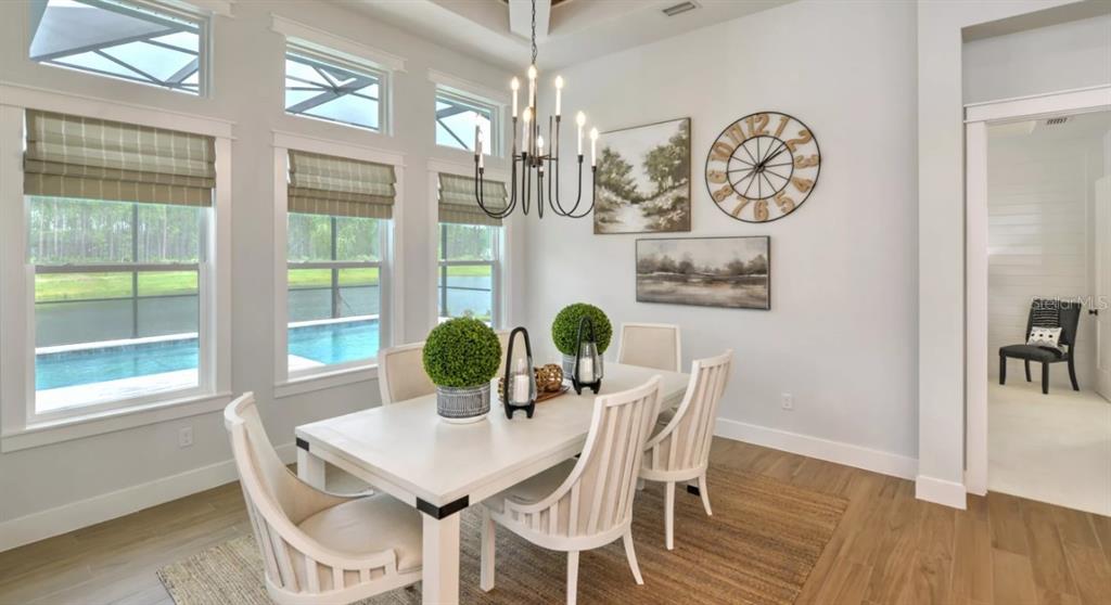 A dining room features a white table, six chairs, a chandelier, and large windows — 443 STIRLING BRIDGE DRIVE, ORMOND BEACH, FL