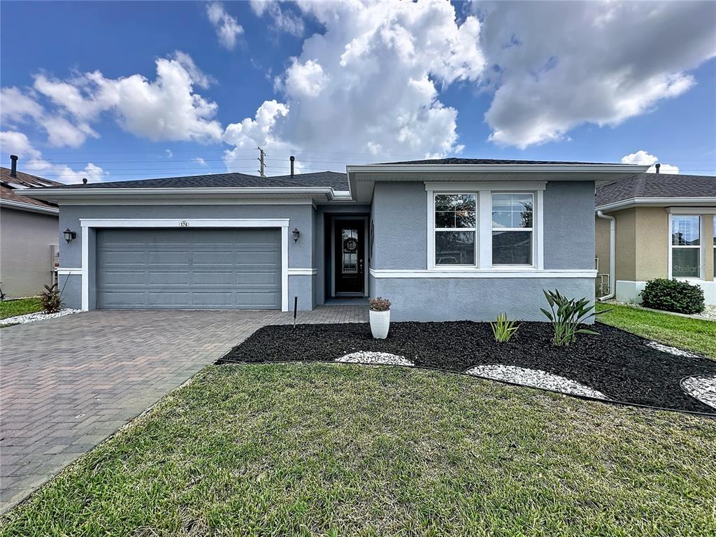 A single-story gray house features a two-car garage, a paved driveway, and a landscaped yard — 174 SILVER MAPLE ROAD, GROVELAND, FL