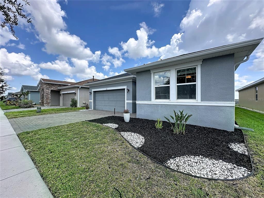 A gray single-story house with a two-car garage and a landscaped front yard — 174 SILVER MAPLE ROAD, GROVELAND, FL