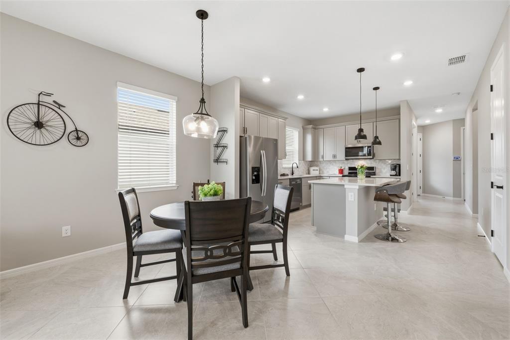A kitchen and dining area with light tile floors, gray cabinets, and a center island — 10462 SPRING TIDE WAY, PARRISH, FL