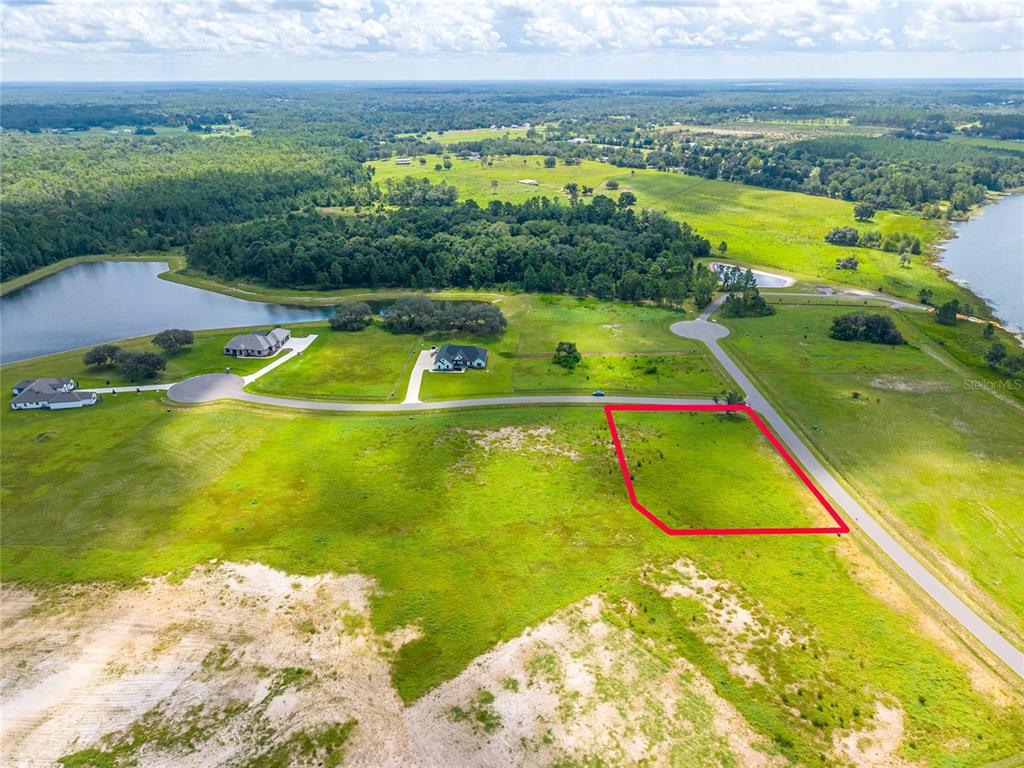 An aerial view shows a vacant, rectangular plot of land outlined in red near a road — 38345 LAKE MEADOW COURT, UMATILLA, FL