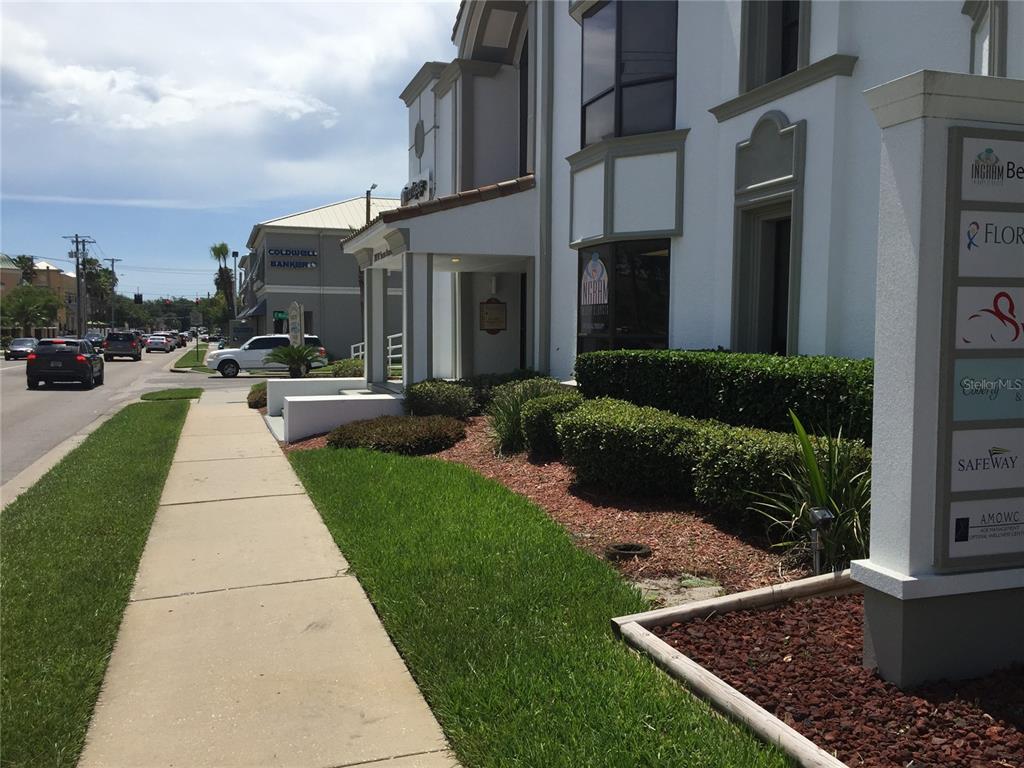 A parking lot with several parked cars, mature trees, and a yellow directional arrow — 2111 W SWANN AVENUE, TAMPA, FL