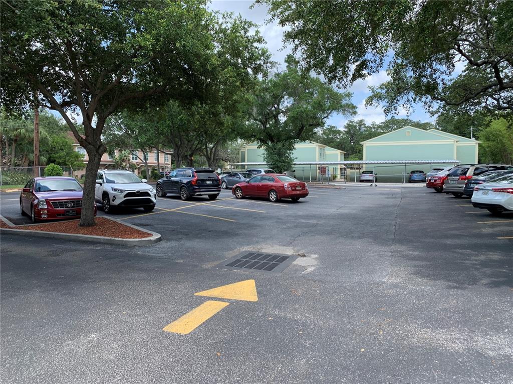 A covered parking garage features concrete pillars, painted yellow curbs, and several parked vehicles — 2111 W SWANN AVENUE, TAMPA, FL